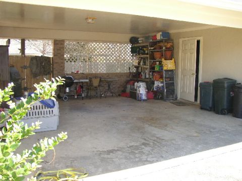 1995 Ford Bronco - A carport scene with various items stored, including shelves, trash cans, and a grill.