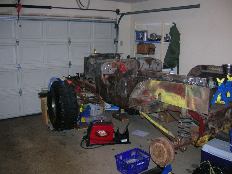 Vehicle chassis on jack stands in garage with welding equipment