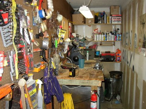1995 Ford Bronco - A cluttered garage workshop scene displays tools, cleaning supplies, and a workbench with various items.
