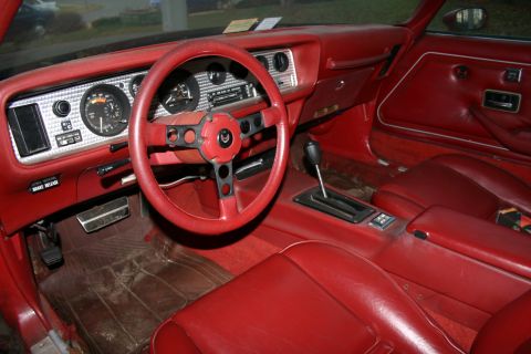 1993 Ford Bronco - The interior of a red car, a distinctive dashboard and steering wheel with a bird emblem.