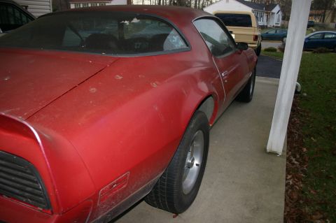 1993 Ford Bronco - A red coupe sits on a concrete driveway, showing its side profile. Houses and other cars are visible in the background.