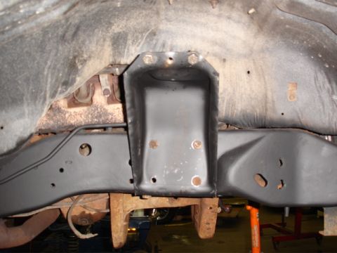 1996 Ford Bronco - A close-up view of a vehicle's undercarriage frame bracket, showing signs of rust and bolted connections.