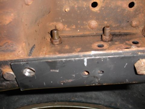 1996 Ford Bronco - Close-up view of a rusted vehicle frame section with bolts and a metal plate.