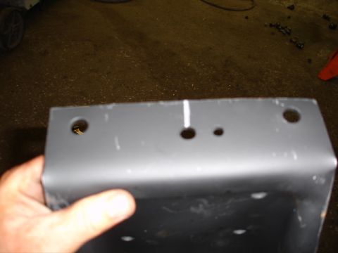 1996 Ford Bronco - A gray metal bracket with multiple holes is held up for inspection.