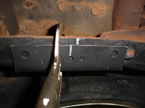 1996 Ford Bronco - A metal plate is secured to a vehicle's frame with a clamp during a modification or repair.