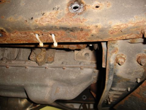 1996 Ford Bronco - The heavily rusted frame and transmission components are visible from underneath the vehicle.