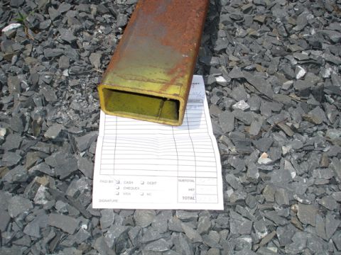 1996 Ford Bronco - A rusty metal tube sits on a receipt and gravel surface.