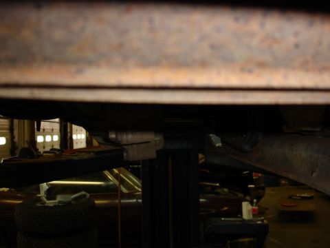 1996 Ford Bronco - The underside of a vehicle is visible, suspended on a lift in a garage setting with other vehicles in the background.