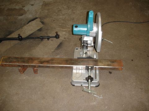 1996 Ford Bronco - A metal cutting saw is positioned next to a tie rod and a metal bar on a concrete floor.