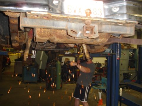 1996 Ford Bronco - A mechanic works on the undercarriage of a vehicle, with sparks flying from welding equipment.