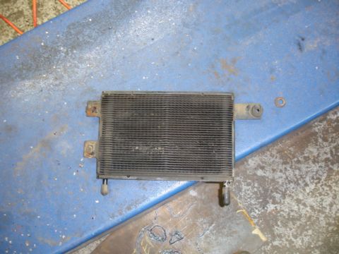 1996 Ford Bronco - A transmission cooler sits on a blue surface, showing its grille and connection points.