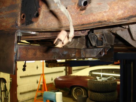 1996 Ford Bronco - Close-up view of vehicle undercarriage components, with another classic car in the background.