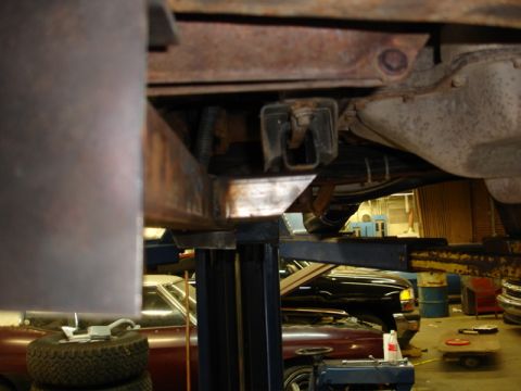 1996 Ford Bronco - The underside of a vehicle is examined on a lift, with other cars in the garage.