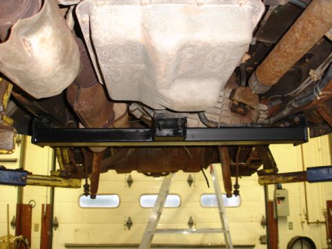 1996 Ford Bronco - The underside of a vehicle is shown, lifted on a mechanic's lift.