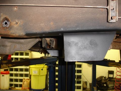 1996 Ford Bronco - Vehicle undercarriage on a lift, displaying frame rust and a protective shield.