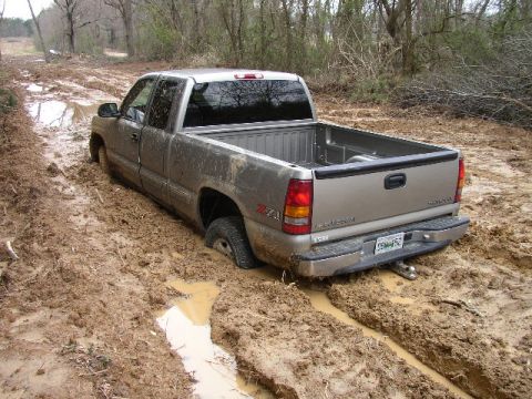 1995 Ford Bronco - Pickup truck is stuck in the mud on a rural road.