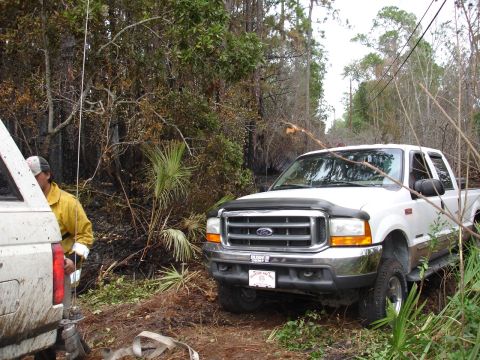 1989 Ford Bronco - A white Ford pickup truck is parked on a dirt road, with a person in a yellow jacket visible on the left.