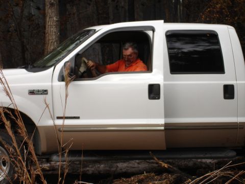 1989 Ford Bronco - A man drives a white Ford F-250 truck through a wooded area.