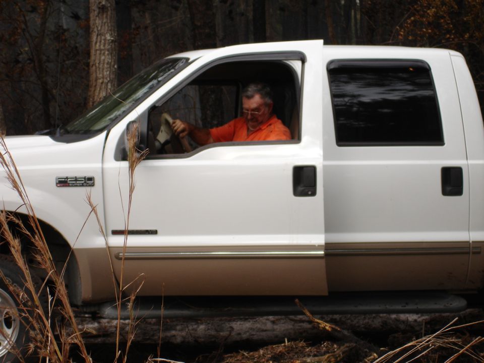 White Ford F-250 truck side view with man driving
