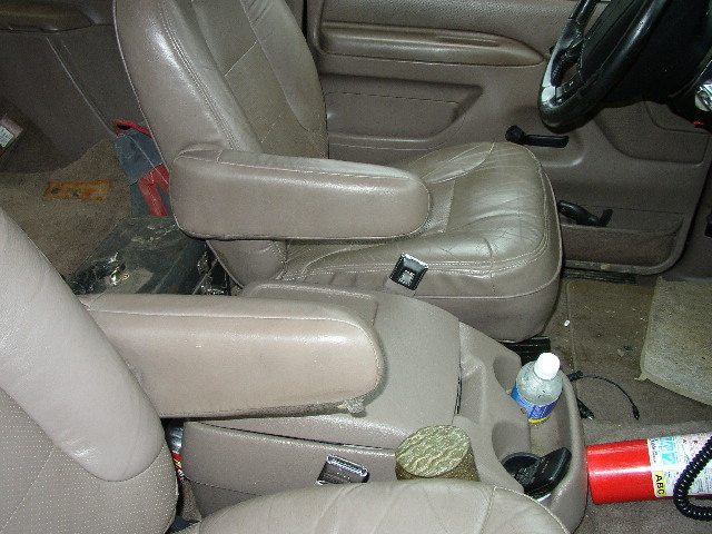 Tan leather driver's seat, steering wheel and floor shift levers inside a truck cab