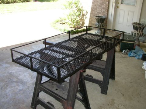 1995 Ford Bronco - A black metal cargo carrier is elevated on sawhorses in front of a building entrance.
