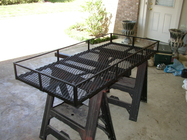 Black metal cargo carrier on sawhorses, viewed from a 3/4 front angle