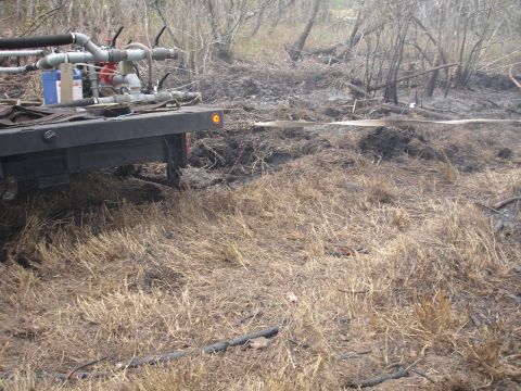 1989 Ford Bronco - A truck equipped with a water pump and hose is positioned in a dry, wooded area, possibly for firefighting efforts.