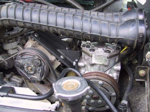 1995 Ford Bronco - Close-up view of engine components including the air intake hose and compressor clutch.