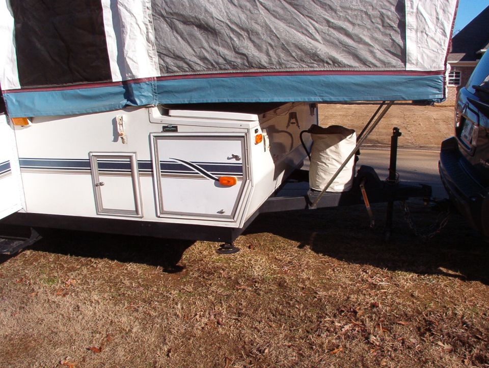 Pop-up camper with blue trim and stripes, hitched to a dark SUV