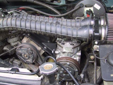 1995 Ford Bronco - Close-up of engine components including air intake and AC compressor.