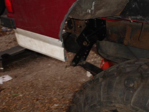 1989 Ford Bronco - Detail of vehicle frame and fender, showing suspension parts and a large tire.