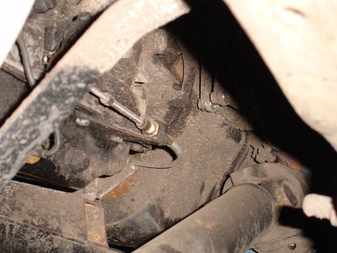 1989 Ford Bronco - Close-up view of the underside of a vehicle, showing mechanical parts and accumulated dust.