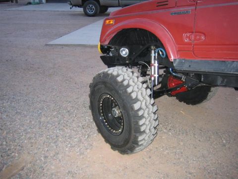 1987 Suzuki Samurai - Close-up of the front wheel and suspension system on a modified 1987 Suzuki Samurai.
