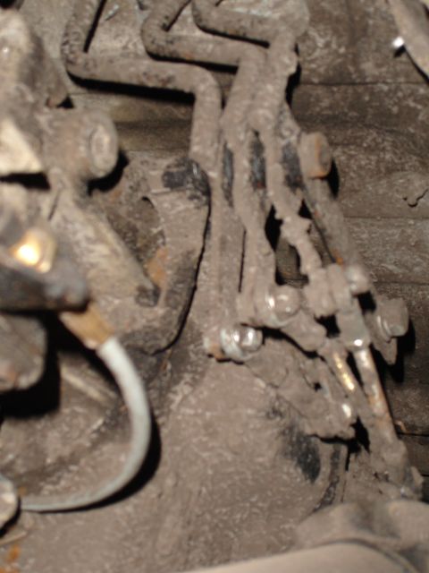 1989 Ford Bronco - This photo shows a section of a vehicle's brake lines, covered in dirt and rust.