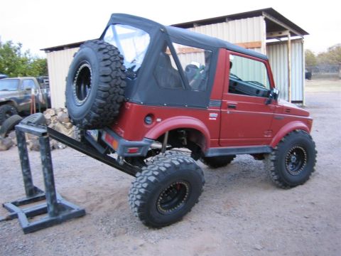 1987 Suzuki Samurai - Red 1987 Suzuki Samurai is positioned on a trailer hitch stand for display or work.