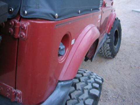 1987 Suzuki Samurai - This red SUV features a soft top and aggressive off-road tires, with a visible fuel cap opening.