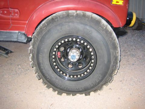 1987 Suzuki Samurai - Close-up of a 1987 Suzuki Samurai's front wheel and fender, fitted with large off-road tires.