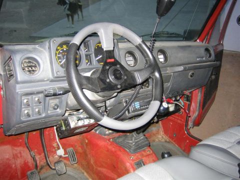 1987 Suzuki Samurai - The interior of a 1987 Suzuki Samurai shows an aftermarket steering wheel and radio, along with a CB antenna.