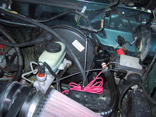 Engine bay showing brake master cylinder, booster, aftermarket cone air filter, and coiled pink wiring