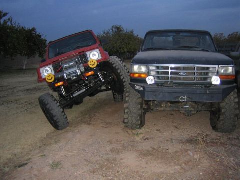 1987 Suzuki Samurai - A modified 1987 Suzuki Samurai is shown off-road next to a dark-colored truck.