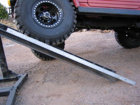 1987 Suzuki Samurai - A ruler is placed on a ramp next to a large tire on a red off-road vehicle.