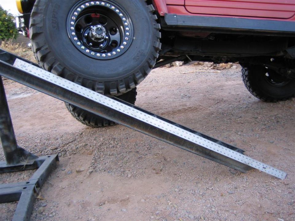 Red 4x4 on a homemade steel RTI flex ramp with beadlock wheel and mud-terrain tire