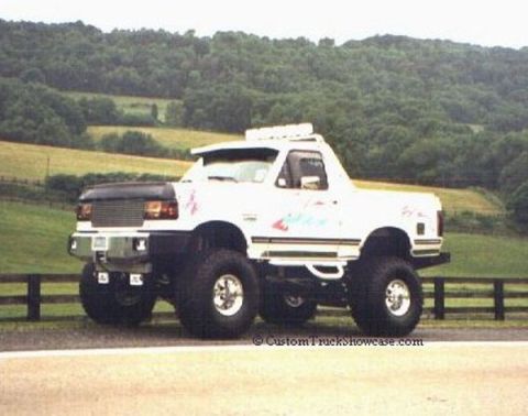 1990 Ford Bronco - A modified 1990 Ford Bronco with oversized wheels and a lifted suspension is seen from a three-quarter front view.