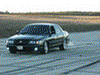 2001 Mercury Grand Marquis - A black 2001 Mercury Grand Marquis sedan is captured in a three-quarter front view as it drives on a dirt track, kicking up dust.