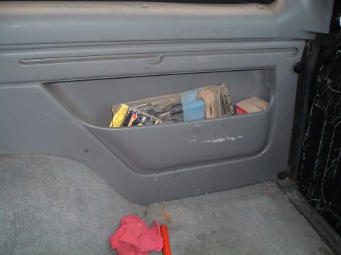1995 Ford Bronco - The interior storage compartment holds various tools and a red rag, with a Supermotors watermark visible.