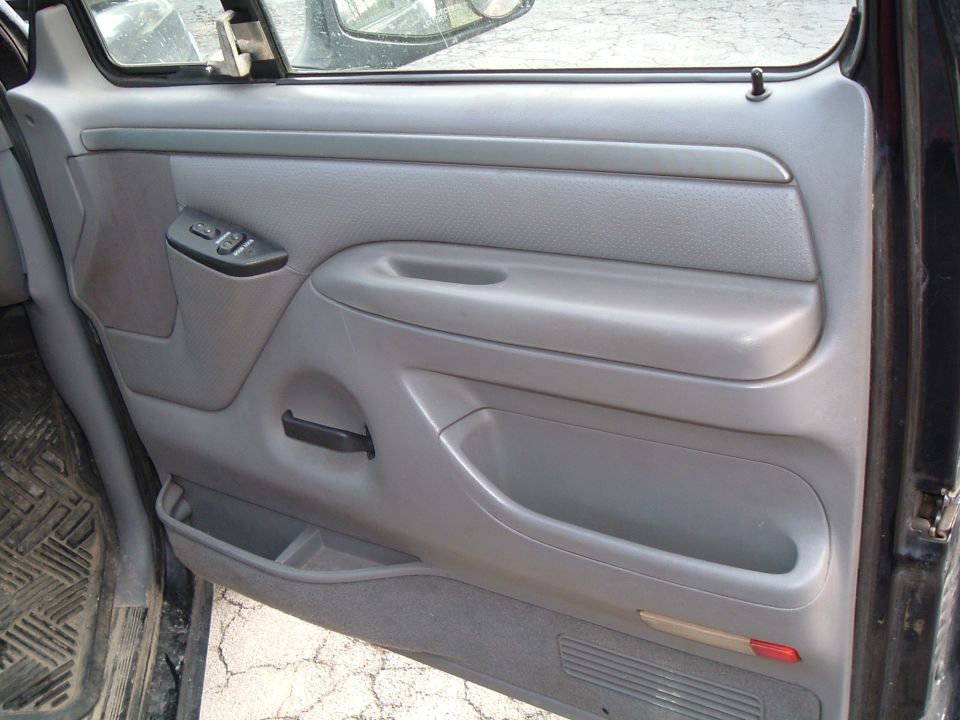Driver's side door panel with power window controls and storage compartments