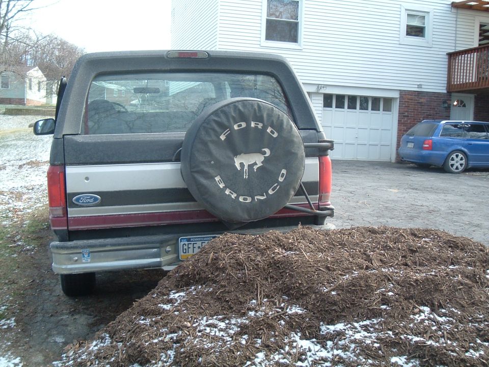 Black Ford Bronco rear with a spare tire cover, parked in a driveway