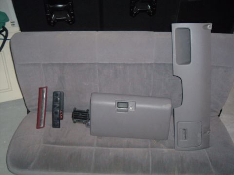 1995 Ford Bronco - Interior parts for a 1995 Ford Bronco XLT, including a glove box, trim pieces, and vent, are laid out on a gray seat.