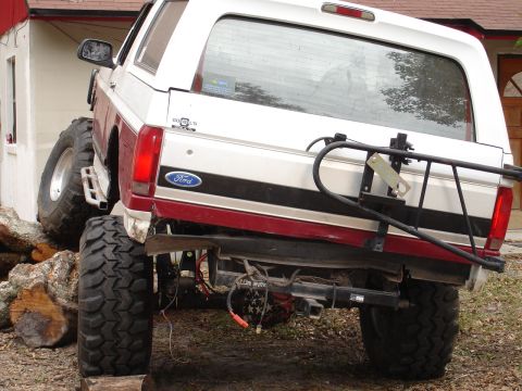 1989 Ford Bronco - Modified 1989 Ford Bronco on logs, showing its rear end and off-road tires.