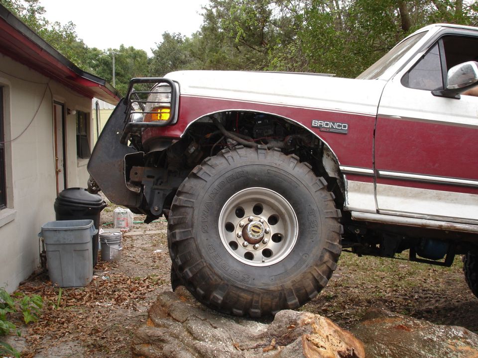 Ford Bronco with large tires, front bumper removed, and a brush guard